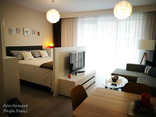 een slaapkamer met een bed, een bank en een tv bij Apartament Magia Rewal in Rewal