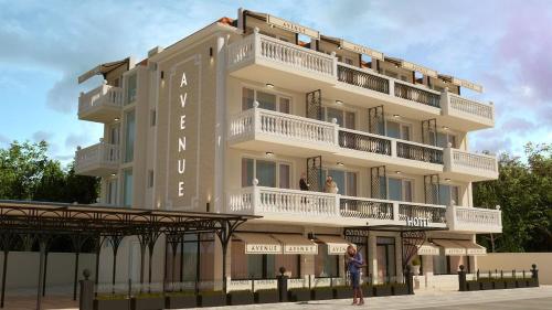 a building with a woman standing in front of it at Hotel AVENUE in Ravda
