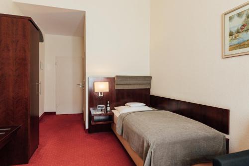 a hotel room with a bed and a red carpet at Hotel de France Wiesbaden City in Wiesbaden