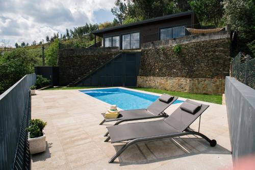 um pátio com 2 espreguiçadeiras e uma piscina em Quinta do Pomar Maior Douro - Porto Carvoeiro em Porto Carvoeiro
