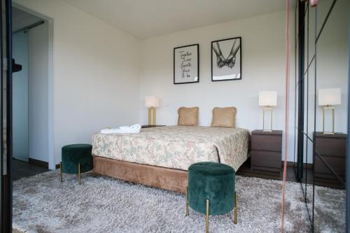 a bedroom with a bed and two green stools at Quinta do Pomar Maior Douro - Porto Carvoeiro in Porto Carvoeiro