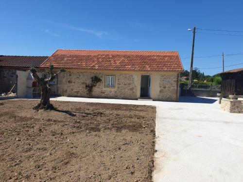 una pequeña casa con un árbol delante en casa CARREGAL, en Tomiño