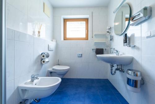 a white bathroom with two sinks and a toilet at Hotel Sonja in Cadipietra