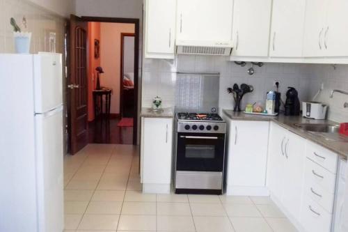a kitchen with white cabinets and a stove top oven at Apartamento Beira-Mar in Ribeira Grande
