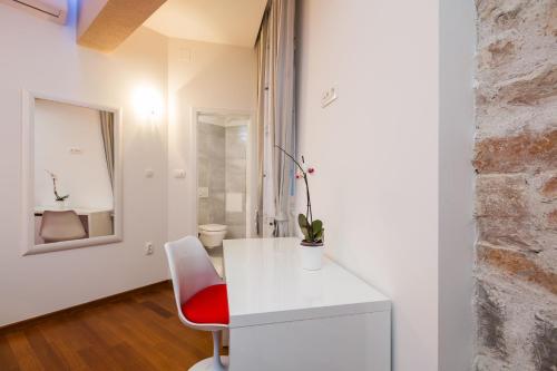 um quarto com uma secretária branca e uma cadeira vermelha em Riva Rooms em Split