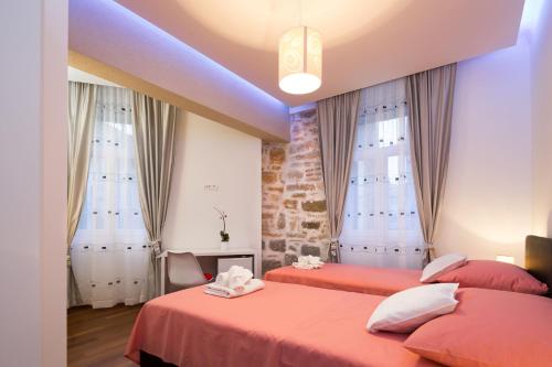 a bedroom with two beds and two windows at Riva Rooms in Split