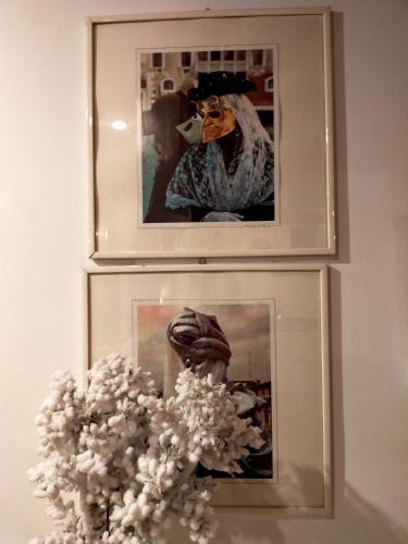 two pictures on a wall with a vase of flowers at Suite Ai Leoni in Venice