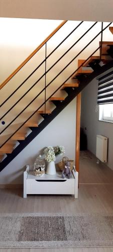 a living room with a staircase and a table with flowers at Apartmani Fenestra Tesla i Faust in Otočac