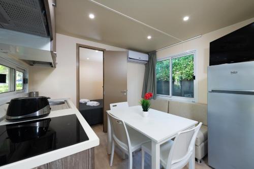 a small kitchen with a white table and a white refrigerator at Luxury Caravan at Union Lido in Cavallino-Treporti