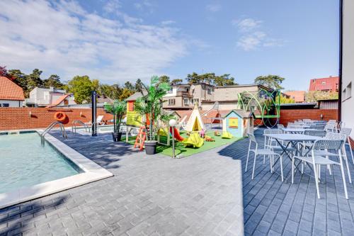a patio with a table and chairs and a playground at Pod Winogronem - Apartamenty z basenem i wyżywieniem in Pobierowo