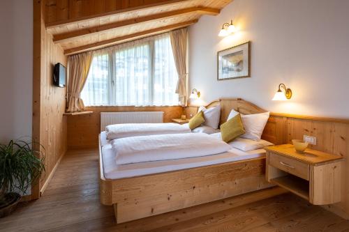 a bedroom with a wooden bed and a window at Apartments Etruska Gabriela in Santa Cristina Gherdëina