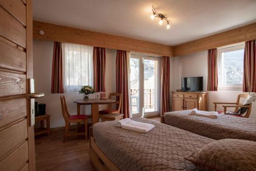 um quarto de hotel com duas camas e uma mesa em Résidence Eureca em Brides-les-Bains