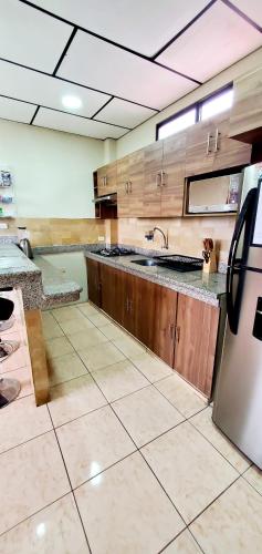 a large kitchen with wooden cabinets and a stainless steel refrigerator at NCG SUITE SAMANES in Guayaquil