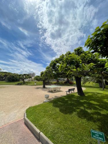 un parc avec un banc et un arbre dans un parc dans l'établissement Beau studio dans résidence avec piscine et vue sur la ville - 5min des plages, à Mandelieu-la-Napoule