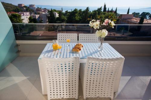 stół z krzesłami oraz wazon z kwiatami i sokiem pomarańczowym w obiekcie Villa Rita w mieście Promajna