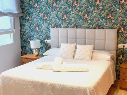 een slaapkamer met een wit bed met bloemenbehang bij Tendillas Suite in Córdoba