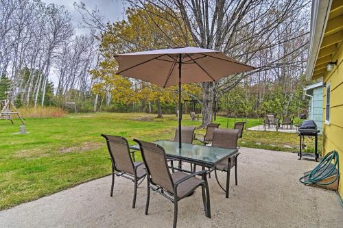a table and chairs with an umbrella on a patio at Pet-Friendly Charlevoix Cabin Walk to Lakefront! in Charlevoix
