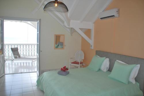 una camera con letto verde e balcone di Le Vanille a Saint-François