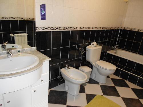 a bathroom with two toilets and a sink and a tub at Vale de Azereiros Apartamentos in Geres