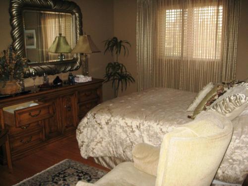 a bedroom with a bed and a mirror and a chair at McDougall Lane Bed & Breakfast in Drumheller