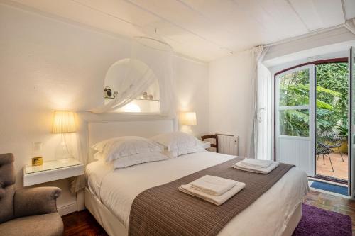 a white bedroom with a bed with towels on it at Casa da Fonte - Holiday Apartments in Cascais