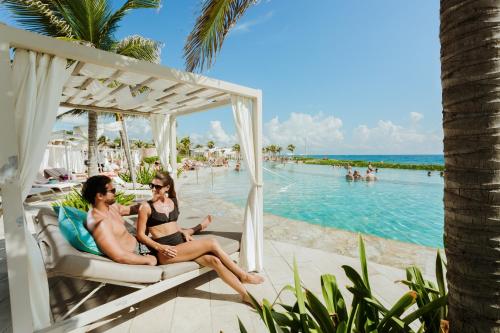 TRS Yucatan Hotel - Adults Only في أكومال: كانتا اثنتان في bikinis جالستان على أرجوحة بجوار المسبح
