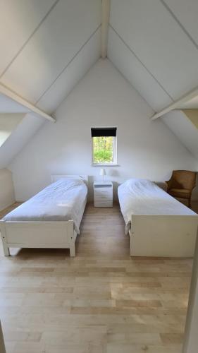 two beds in a white room with a window at Het Roodborstje in Otterlo