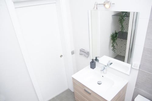 a white bathroom with a sink and a mirror at Sweet Stays in Las Palmas de Gran Canaria