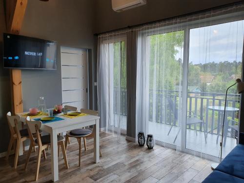 d'un salon avec une table blanche et un balcon. dans l'établissement Willa Zacisze apartament 12, à Kąty Rybackie