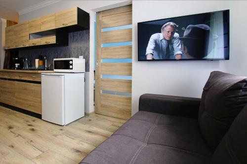 a living room with a couch and a tv on a wall at Apartament Navigare in Kołobrzeg