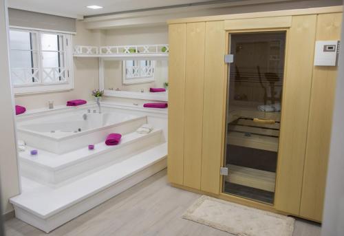 Villa Rita Apartments II في بروماجنا: حمام كبير مع حوض استحمام ومغسلة