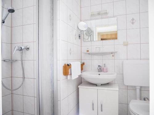 uma casa de banho branca com um lavatório e um chuveiro em 5Rooms Frühstückspension em Sankt Stefan im Rosental