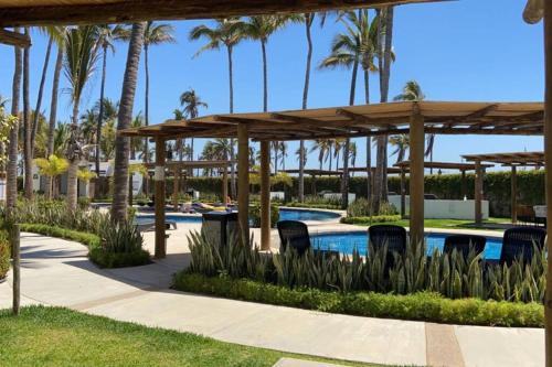 a pool at the resort with chairs and palm trees at Modern Decor Apartment near ocean in Mazatlán