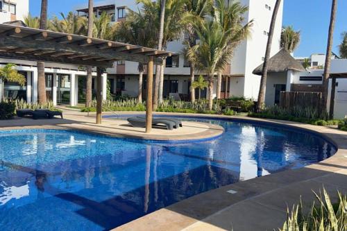 a swimming pool with a pergola next to a building at Modern Decor Apartment near ocean in Mazatlán
