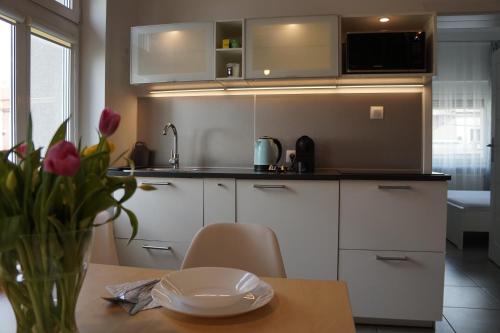a kitchen with white cabinets and a table with a vase of flowers at Apartament Gliwice Centrum Fredry I in Gliwice