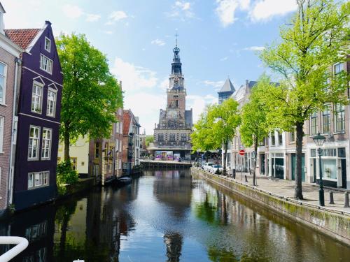 une rivière dans une ville avec une tour de l'horloge dans l'établissement Groenlokaal, à Alkmaar