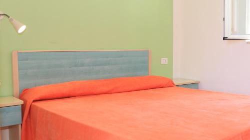 a bed with an orange blanket on top of it at Villaggio Elisena in Vieste
