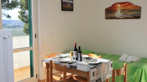 a table with a green table cloth and bottles of wine at Villaggio Elisena in Vieste