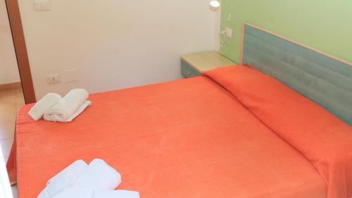 a bedroom with an orange bed with two white towels at Villaggio Elisena in Vieste