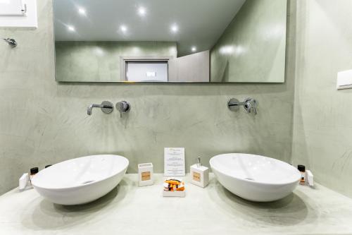 two white sinks in a bathroom with a mirror at Casa Reale in Fira
