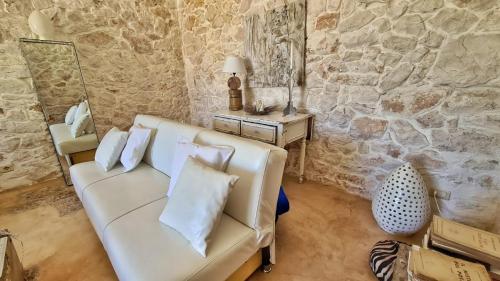 a living room with a white couch and a stone wall at Pietrefitte in Ostuni