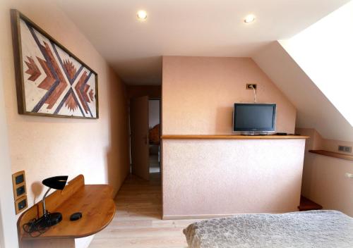 a room with a bed and a tv on a wall at Auberge de la Rivière in Foncine-le-Haut