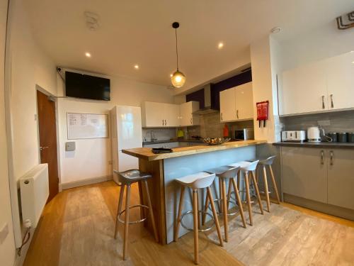 a kitchen with a counter and bar stools at 77 Underwood Lane in Crewe