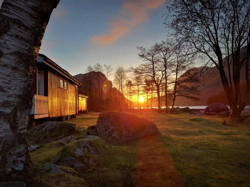 un tramonto in un campo con una casa e un albero di Wathne Camping a Bjørheimsbygda