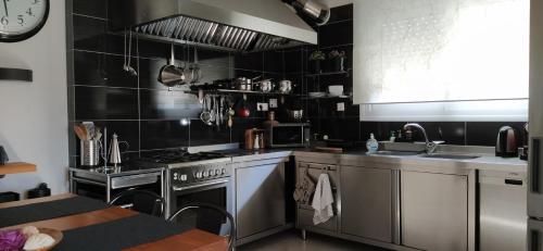 a kitchen with stainless steel appliances and black tiled walls at Villa Tsios in Artemida