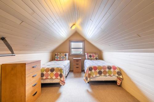 a attic bedroom with two beds and a dresser at Bayside Cottage Rentals in Port Rowan