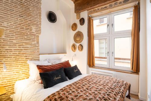 a bedroom with a bed and a brick wall at Honorê, Suite Saint Georges in Lyon