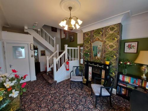 a hallway with a staircase with chairs and a book shelf at The Hilary Guesthouse in Llandudno