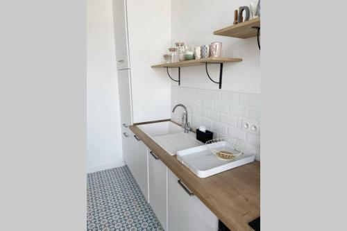 a white kitchen with a sink and a counter at Sur le bord du quai in Sète