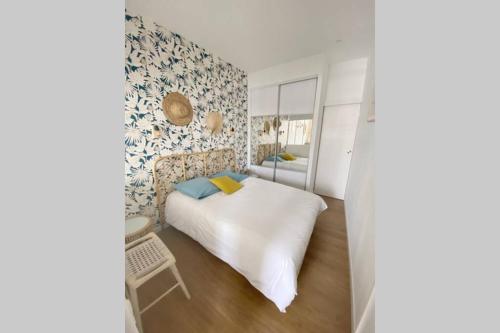 a bedroom with a white bed and blue and white wallpaper at Sur le bord du quai in Sète